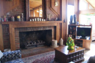 sitting rooms with double-wide brick fireplace with mirror hanging above with coffee table and entertainment center with television