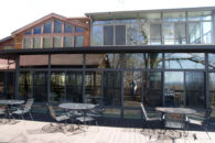 black metal patio tables on wooden desk next to multi-level building with extensive windows