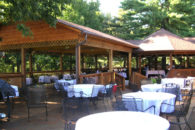 tables covered with white linen cothes on patio and underneath covered decks set up for wedding celebration